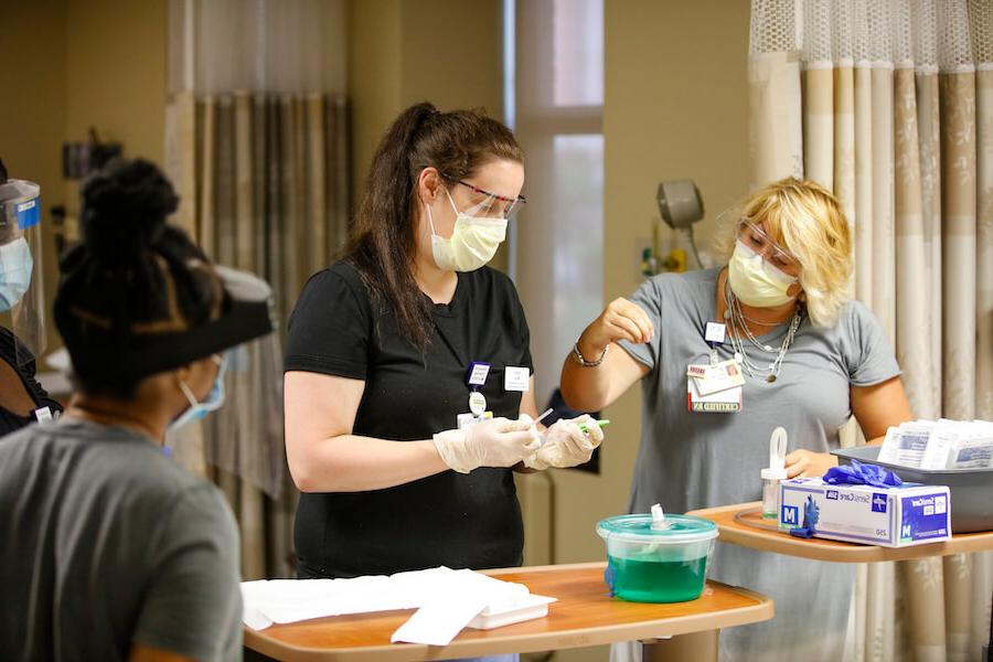 A University of Rochester School of Nursing student is being taught how to handle medical equipment in a hospital setting.